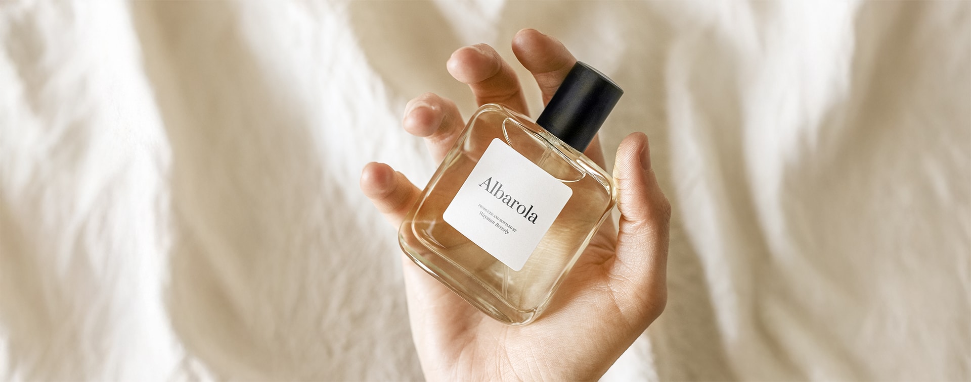 a person holding a perfume with his hand